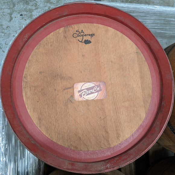 Wooden barrel with red rim and 'BeerCo' label on a concrete surface
