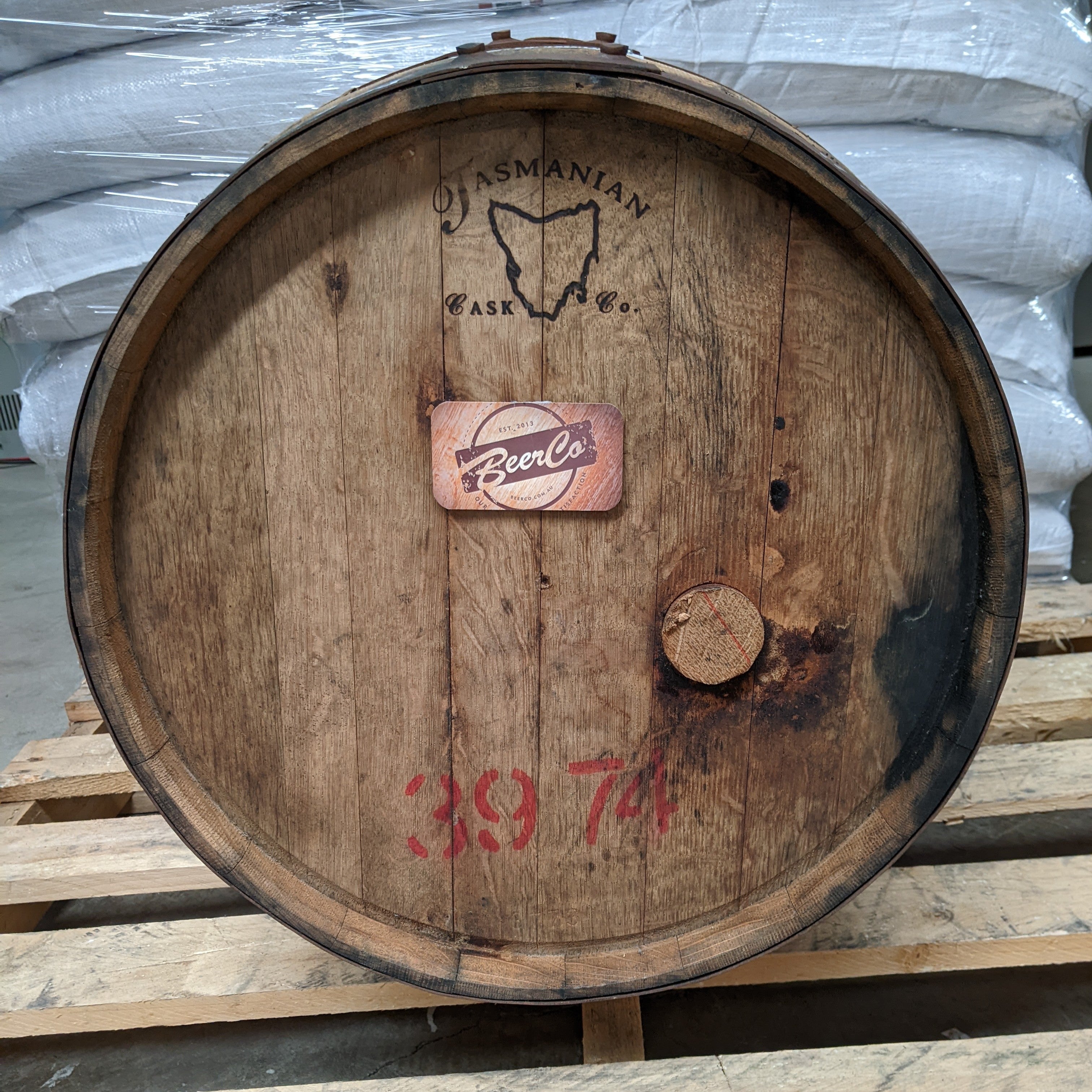 Wooden barrel with 'Australian Cask' and 'BeerCo' branding on a pallet.