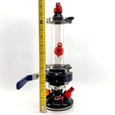Clear cylindrical device with red and blue components, height measured by a tape measure on a white background