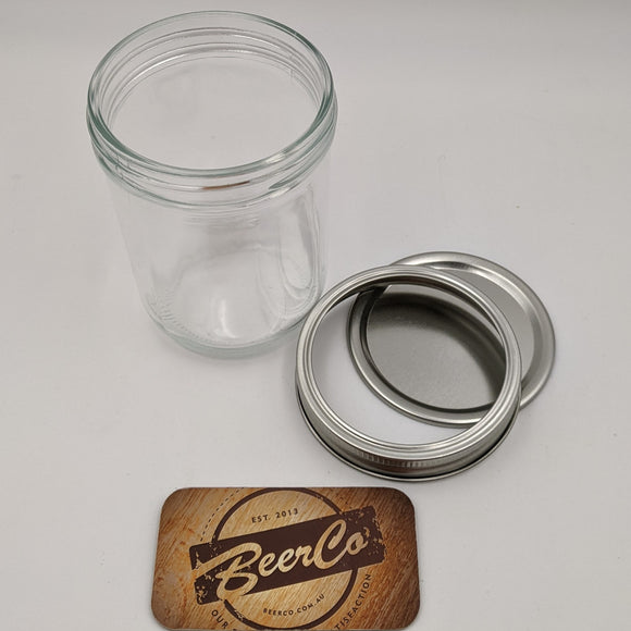 Clear glass jar with metal lid and wooden coaster featuring 'BeerCo' logo on a white background