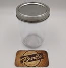 Clear glass mason jar with metal lid on a white background, featuring a 'BeerCo' branded coaster.