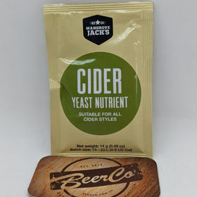 A sachet of Mangrove Jack's Cider Yeast Nutrient placed on a wooden surface with a branded object in the background.