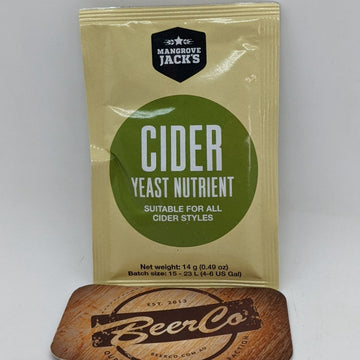 A sachet of Mangrove Jack's Cider Yeast Nutrient placed on a wooden surface with a branded object in the background.