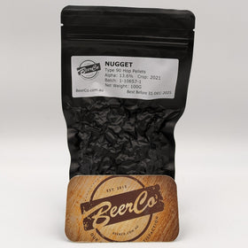 Black bag of BeerCo pellets with a wooden coaster featuring the BeerCo logo on a white background