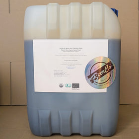 A large plastic drum labeled with the 'Best Ground' brand, containing organic raw 100% blue agave syrup.