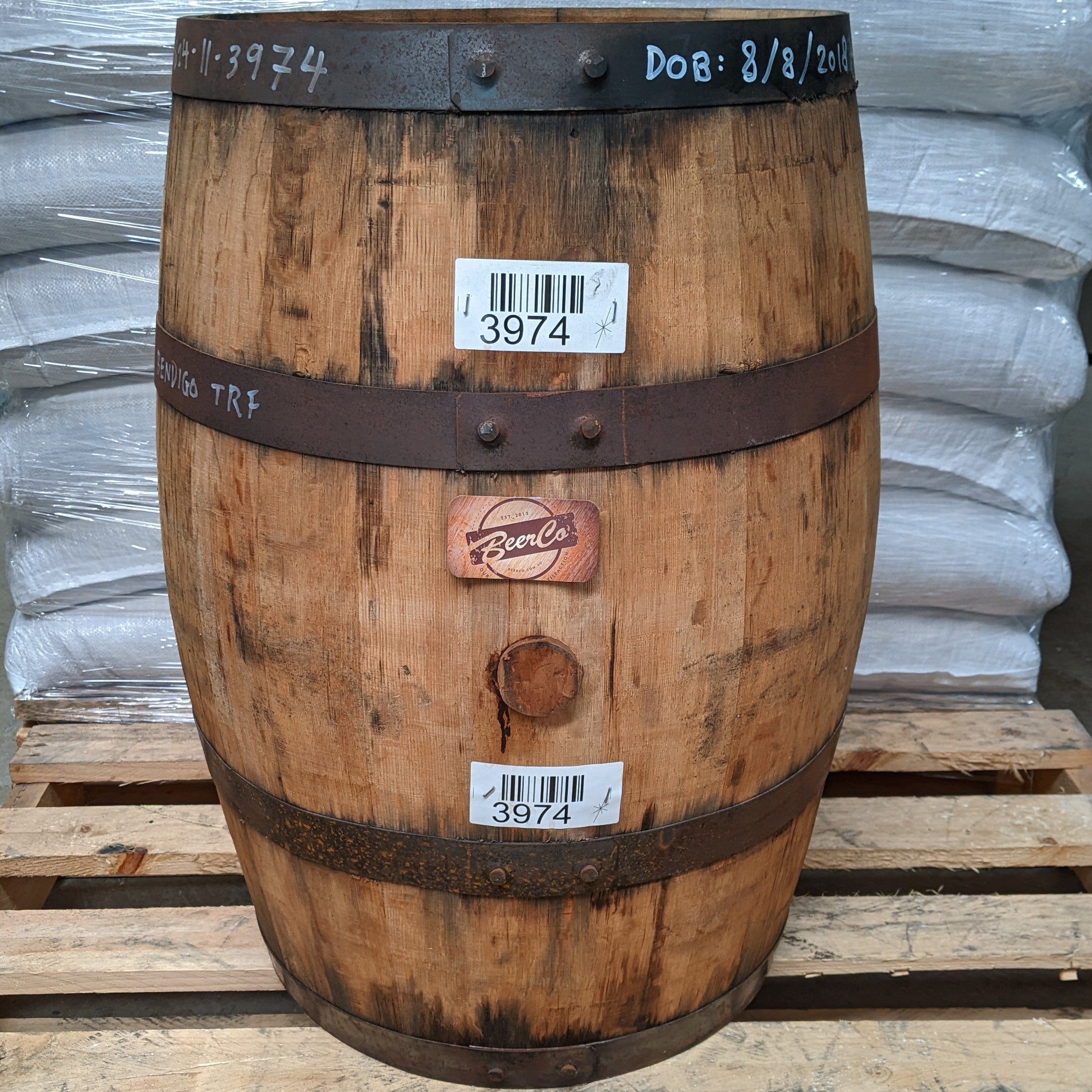 Wooden barrel with labels and a visible brand logo on a pallet.
