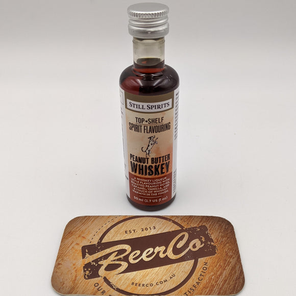 Bottle of Still Spirits Peanut Butter Whiskey on a wooden coaster with 'BeerCo' branding.