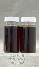 Two jars of dark liquid with white lids on a gray background