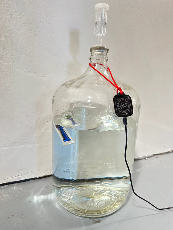 Clear glass bottle with a black device attached, on a white surface.