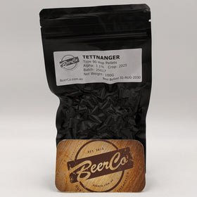 Black bag of Tettnanger hop pellets with a wooden coaster featuring BeerCo logo on a white background