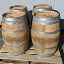 Four wooden barrels with metal bands on a wooden pallet against a gray background
